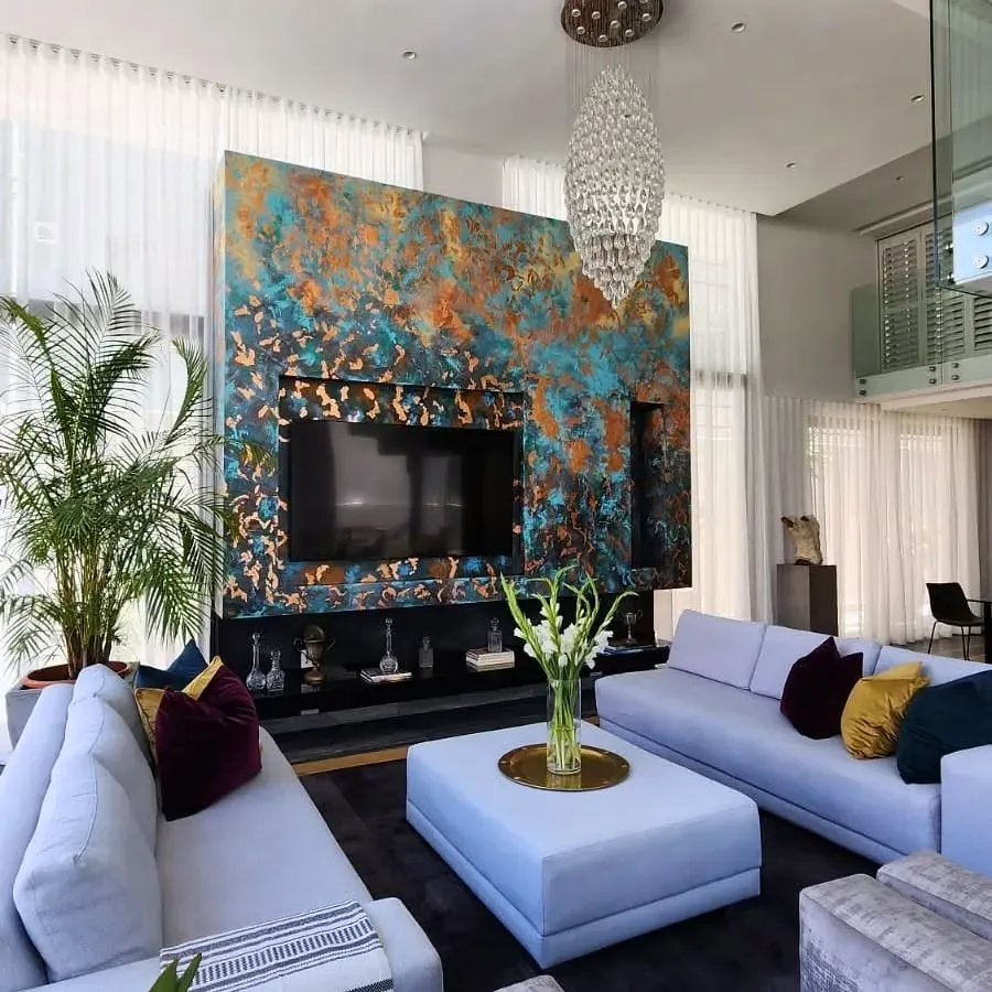 Photograph: a double-height living room in Bantry Bay, with Linda Wolf’s teal and copper wall behind pale sofas.