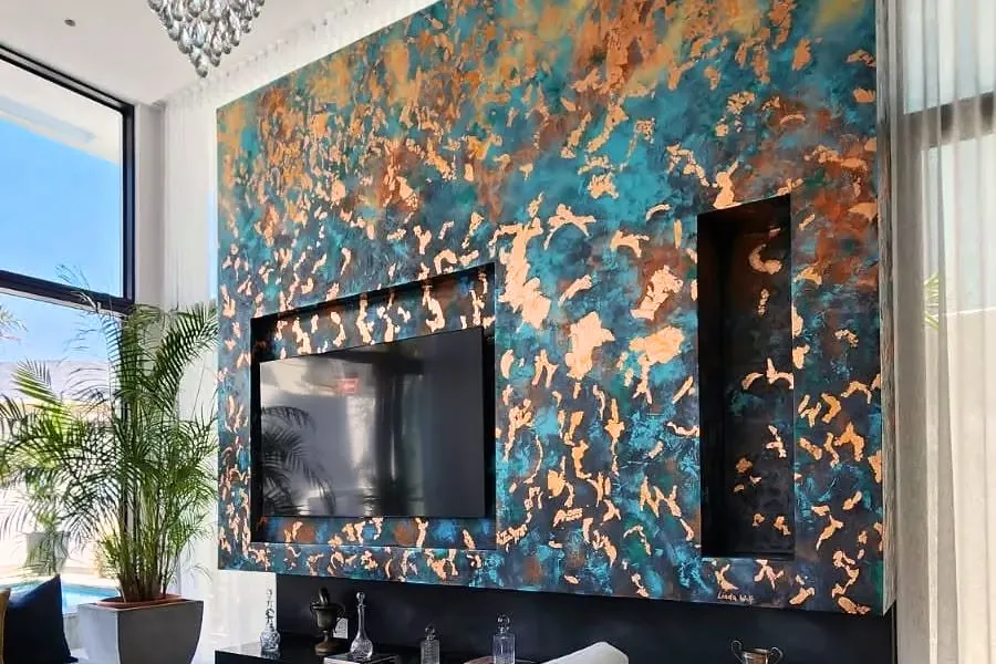 Photograph: Linda Wolf’s painted feature wall in Bantry Bay, teal and copper around a television and a narrow recess.