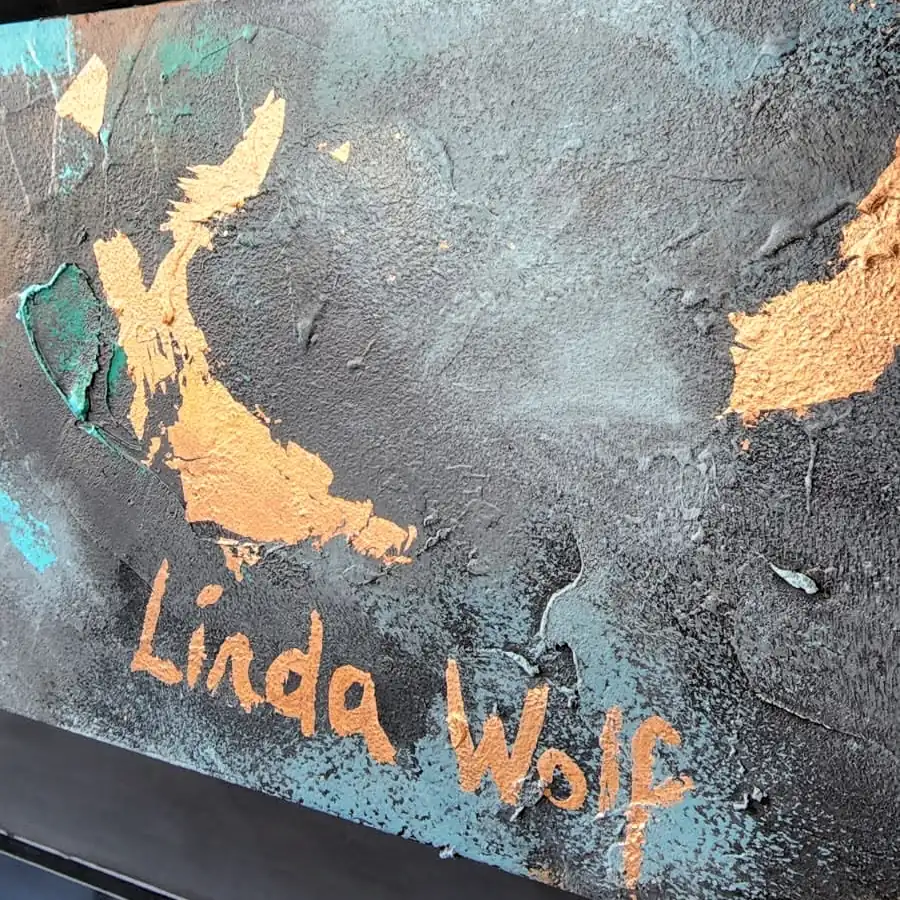 Photograph: Linda Wolf’s signature in copper-coloured letters on a dark wall flecked with teal and copper.