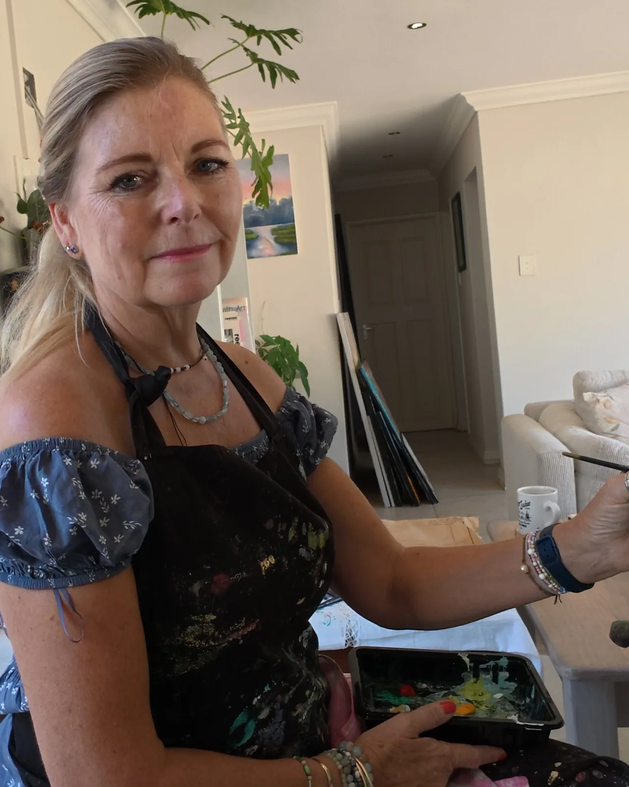Linda smiles at the camera, brush in hand.